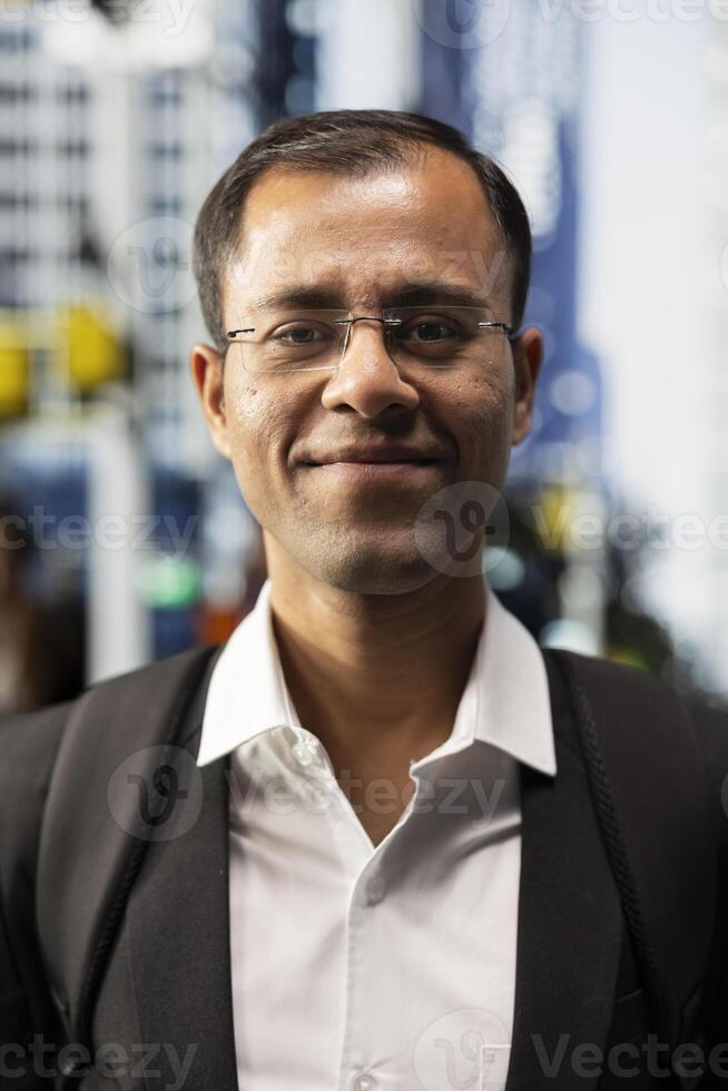 portrait of indian businessman in suit standing on the sidewalk downtown walking across metropolitan area business district male professional on a busy crowded street during commute photo